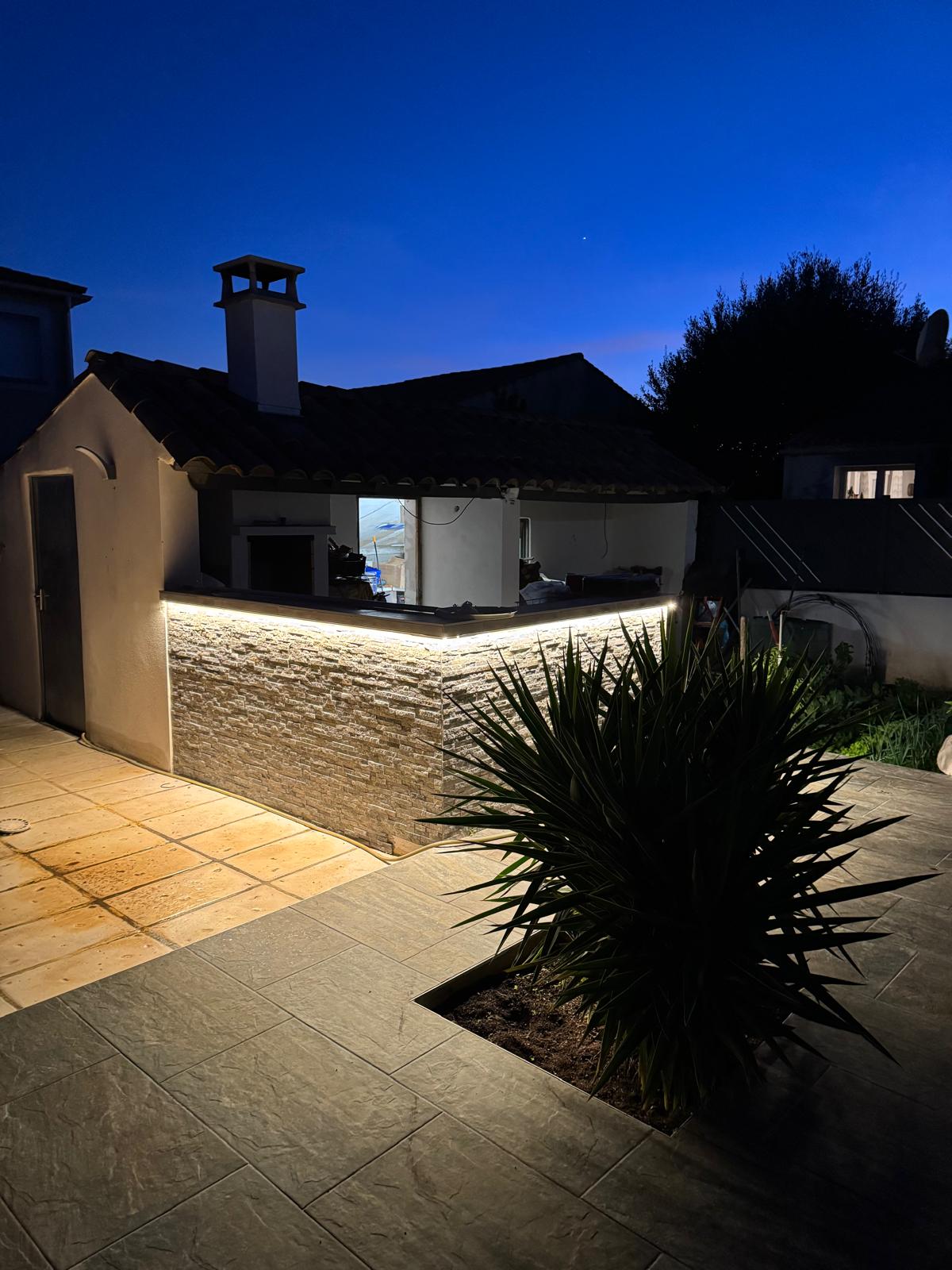 Éclairage LED extérieur en bandeau sur muret en pierre de nuit